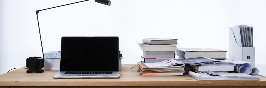 A desk with books, a laptop, and a notepad